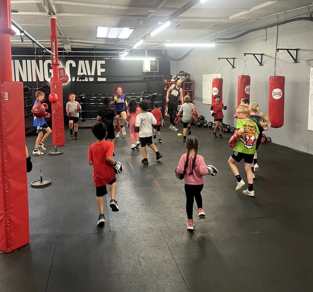 Young students practising pad work drills across the gym floor